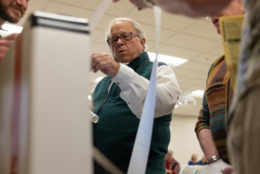 Gillespie County elections administrator, Jim Riley, holds results from the mock election as the ballot scanner releases the information on Feb. 6, 2024. Results were read to county residents following the mock election.