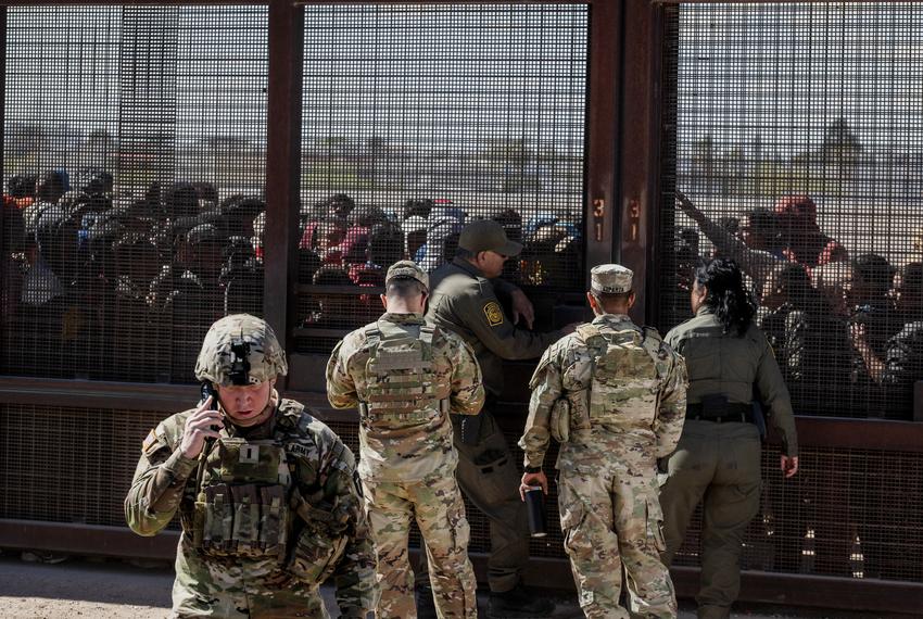 Members of the Texas National Guard work with Border Patrol to coordinate migrants who crossed the border from Mexico and forced their way through concertina wire while they wait to be processed by border patrol as they are stopped on the U.S. side of the Rio Grande, in El Paso on March 21, 2024.