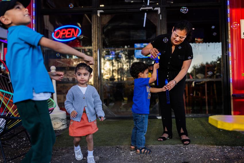 Susana Cazares, 49, Leo’s Beer Barn owner in Cleveland, helps her nephew Santiago Lopez, 3, blow bubbles at her business on April 12, 2024, in Cleveland. The longtime Colony Ridge resident, Cazares, fostered her entrepreneurial spirit in the development and included her family in the business growth.