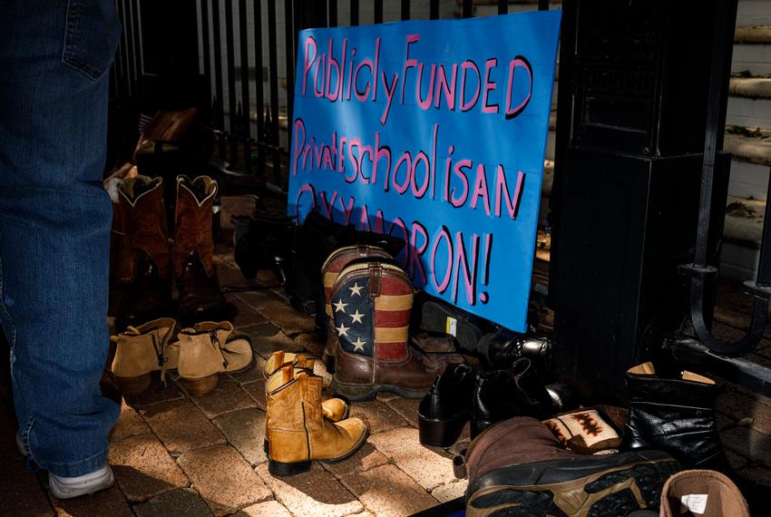 A protester, left, pauses to leave a boot at the steps of the Governor's Mansion during a rally to "boot vouchers" on Oct. 7, 2023. Hundreds gathered to protest two days before a special session was slated to begin on Oct. 9, 2023.