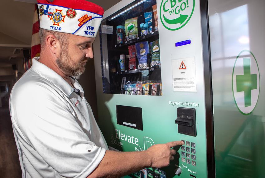 Dave Walden, wearing a Veterans of Foreign Wars cap demonstrates how the CBD vending machine works by purchasing a product, in Leander on Nov. 1, 2022.