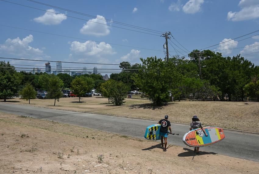 Paddleboarders walk to Barton Springs on July 13, 2022.