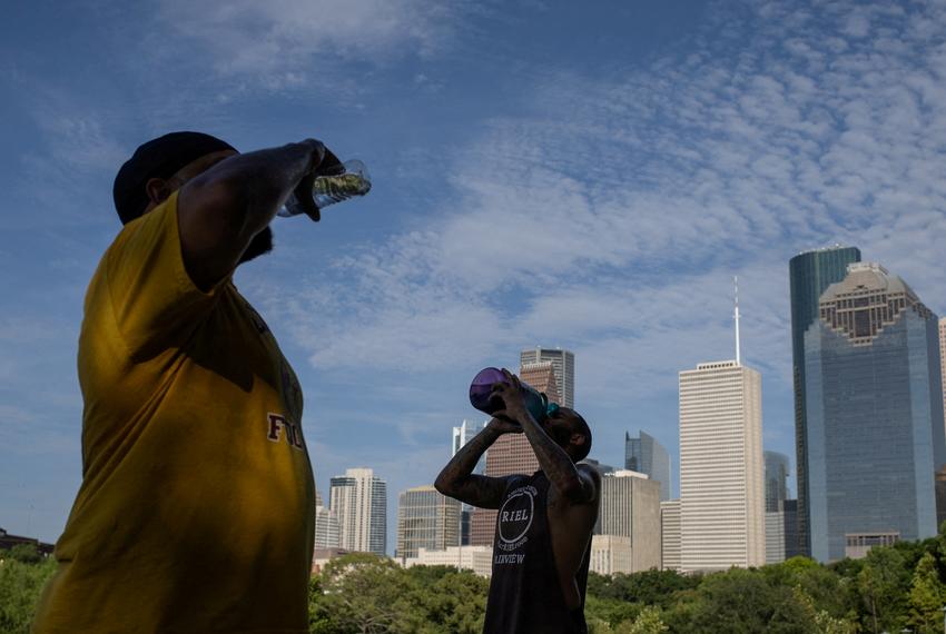 Val Martin and Ashford Joseph rehydrate after climbing stairs in Eleanor Tinsley Park as temperatures hit 100 degrees Fahrenheit in Houston, on July 12, 2023.