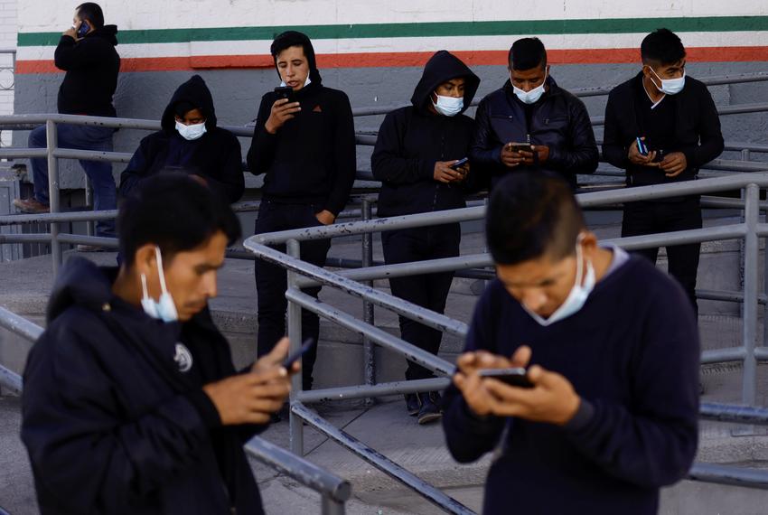 Migrants expelled from the U.S. and sent back to Mexico under Title 42, use their phones near the Paso del Norte International border bridge, in Ciudad Juarez, Mexico May 21, 2022.